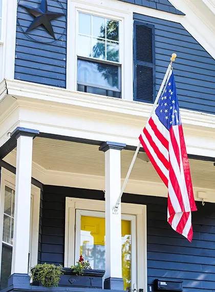blue house flying the US flag representing using VA loans to purchase home